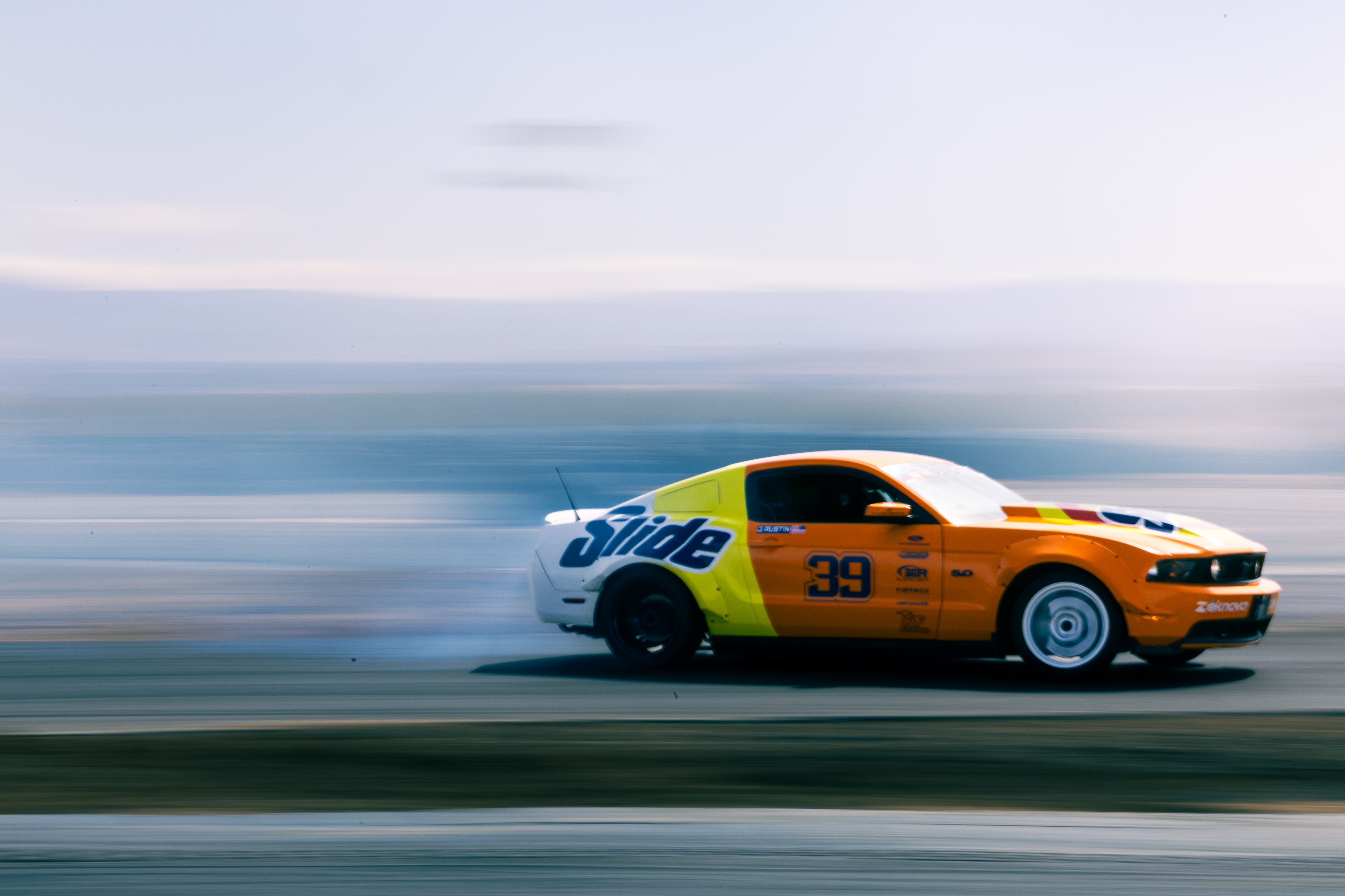 A Ford Mustang drifting through a cloud of tire smoke.